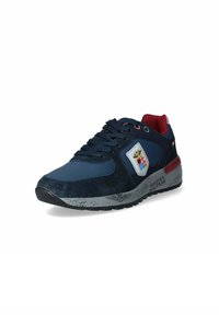 Sneaker blu navy con tomaia in suede e mesh. Presenta un patch con logo, accenti rossi e una suola texturizzata. I lacci sono di un blu scuro.