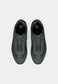 Szare zamszowe trampki z ciemnozielonymi akcentami, teksturowanymi nakładkami i tonowanymi sznurowadłami. Logo "BOSS" na językach; wyściełane wkładki.