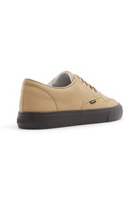 Sneaker in tela beige con profilo basso, punta rotonda, suola in gomma nera e occhielli in metallo; tallone rinforzato e branding discreto sul lato.