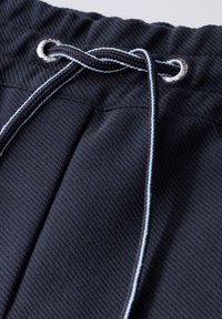 Marineblauwe sweatpants van textuurstof, met een trekkoord met zilveren ringen en lichtblauwe accentstiksels.