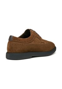Scarpe in suede marrone con dettagli perforati e suola in gomma nera. Presentano una punta arrotondata e contrasti in pelle scura.