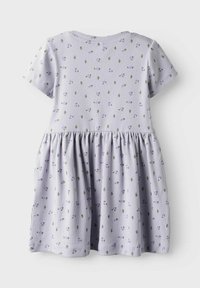 Valkoinen lyhytniminen, laventelin värinen mekko, jossa on ribbitekstuuri ja kukkakuosi purppuran ja vihreän sävyissä. Helma on liehukantyyppinen ja siinä on rypytetty yksityiskohta.