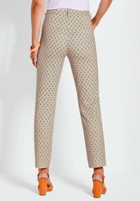Pantaloni a fantasia in arancione, blu e crema con un design a rombo. Fit slim con vita a media altezza, abbinati a sandali con tacco a blocco arancioni.