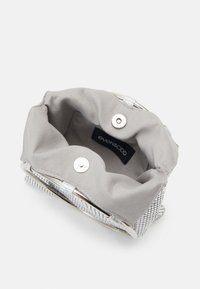 Petit sac à main en maille argentée ouverte avec doublure en tissu gris et fermetures magnétiques.