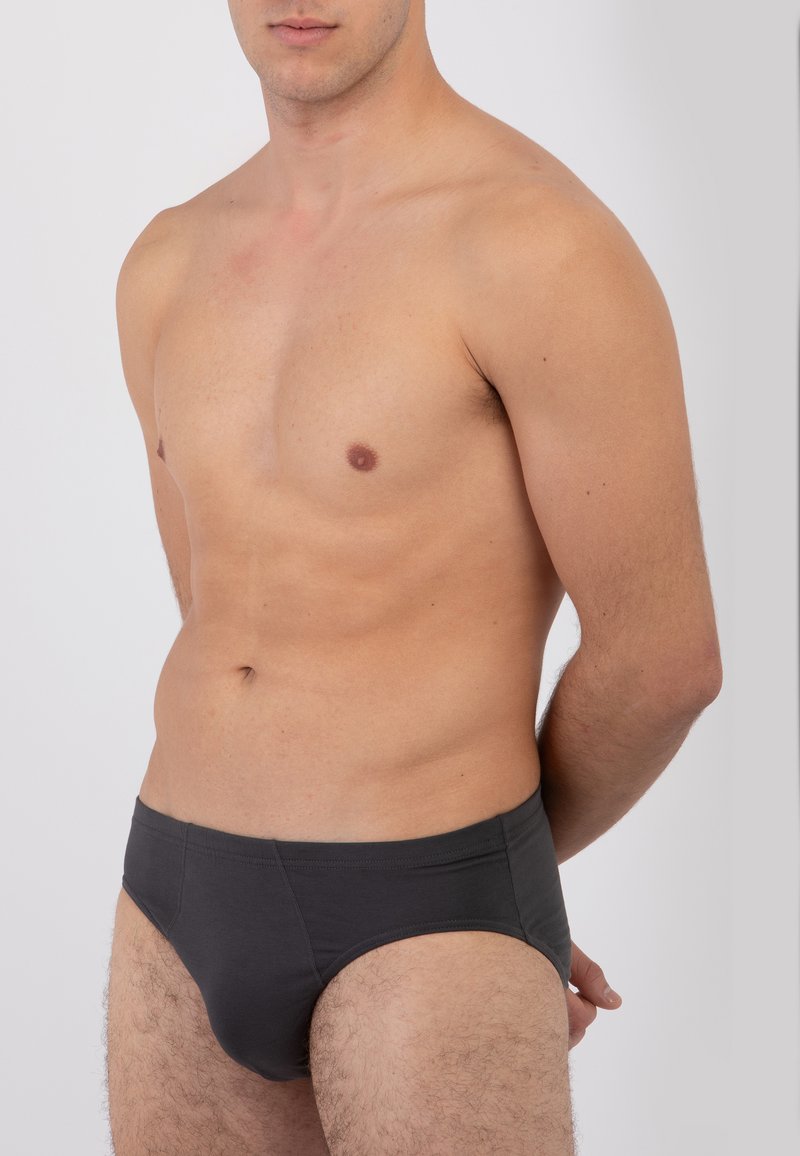 Slip in cotone grigio con texture liscia, design a vita bassa e cuciture laterali. Il tessuto ha una leggera lucentezza, con branding minimalmente visibile.