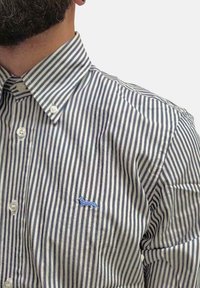 Camicia a righe bianca e blu navy, con colletto a button-down. Presenta un logo di cane ricamato di colore azzurro chiaro sul lato sinistro del petto. Tessuto morbido al tatto.