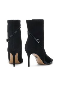 Botas de tobillo negras de ante con detalles en piel de charol brillante, tacones altos tipo stiletto y una correa con hebilla en el costado.