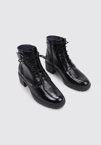 Botines de charol negro con cordones y detalle de hebilla lateral, con un tacón grueso y superficie texturizada.