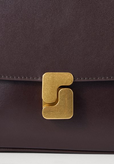 Borsa in pelle marrone con un chiusura geometrica dorata. La borsa presenta una superficie liscia con cuciture sottili lungo i bordi.