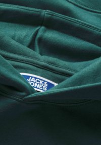 Felpa verde con cappuccio, dalla texture liscia, che presenta un'etichetta con la scritta "JACK & JONES" in bianco su sfondo blu.