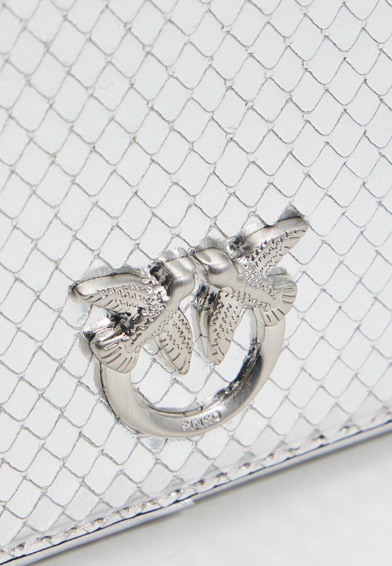 Srebrna torebka z łuskowym wzorem, z metalowym zapięciem w kształcie ptaka jako wyróżniający się detal. Gładka faktura i usztywniony fason.