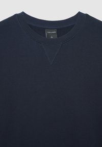 Felpa blu navy con scollo a costine e dettaglio a punto V. Realizzata in tessuto morbido, presenta un'etichetta con il nome del marchio e la taglia.