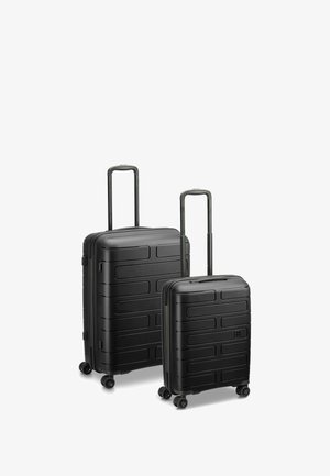 Due valigie rigide nere di diverse dimensioni, con superfici texturizzate caratterizzate da scanalature orizzontali e manici telescopici, su quattro ruote.