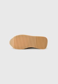 Semelle de chaussure en caoutchouc avec texture striée, présentant un bout arrondi et une couleur beige clair, conçue pour l'adhérence et la stabilité.