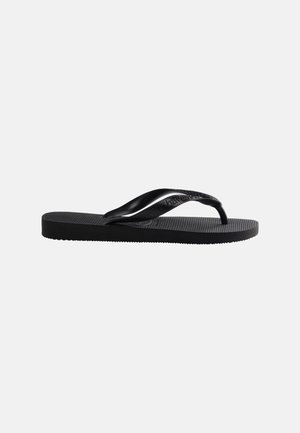 Tongs en caoutchouc noir avec semelle texturée et bride en forme de Y arborant un logo de marque subtil sur un fond uni.