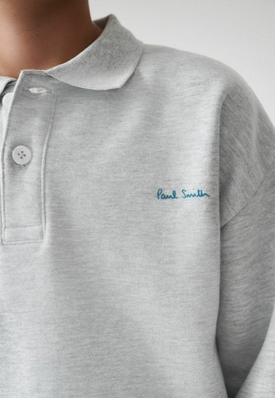 Šviesiai pilkas polo marškinėliai, pagaminti iš švelnios medžiagos, su klasikinio tipo apykakle, dviem mygtukais ir išsiuvinėtu žydru "Paul Smith" logotipu.