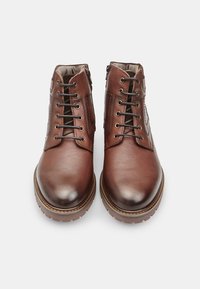 Stivaletti in pelle marrone con finitura liscia, con lacci sul davanti e zip laterale. Presentano una suola robusta con un leggero tacco e cuciture a contrasto.