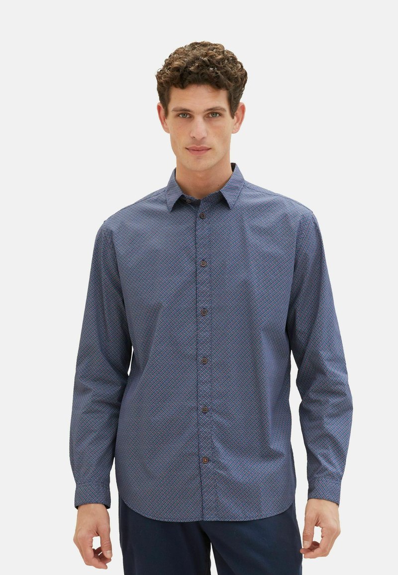 Marineblaues Langarmhemd mit geometrischem Muster, Button-Down-Kragen und braunen Knöpfen, aus leichtem Stoff gefertigt.