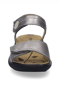 Stříbrné kožené sandály s nastavitelným páskem, tvarovanou stélkou a černou gumovou podrážkou. Dekorativní listový vzor na polstrované stélce.