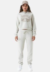 Hellgraues, kurzes Hoodie mit "NEW ERA NEW YORK" Druck, passenden Sweatpants und einer Mütze. Es hat einen lässigen Schnitt und eine Kordelzugdetail.
