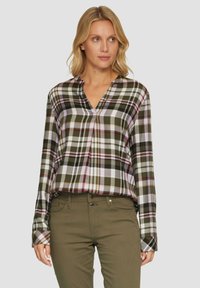 Geruite button-up blouse in groen, wit en burgundy; lange mouwen, v-hals, zachte stof met een relaxte pasvorm; gecombineerd met olijfgroene broeken.