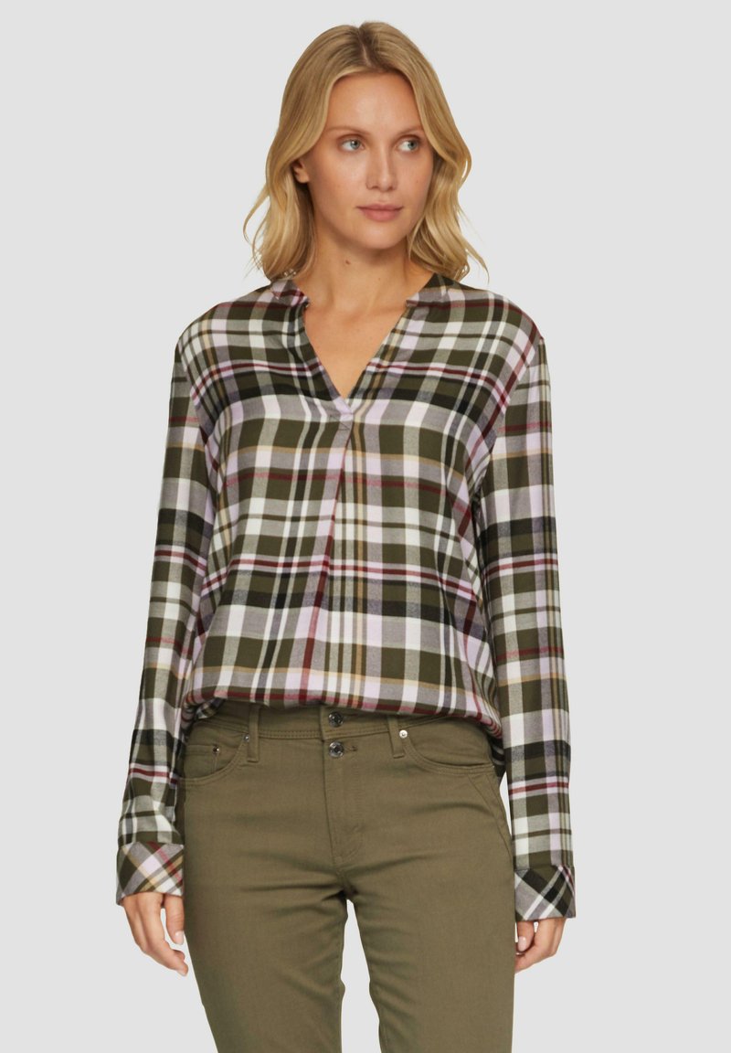 Geruite button-up blouse in groen, wit en burgundy; lange mouwen, v-hals, zachte stof met een relaxte pasvorm; gecombineerd met olijfgroene broeken.