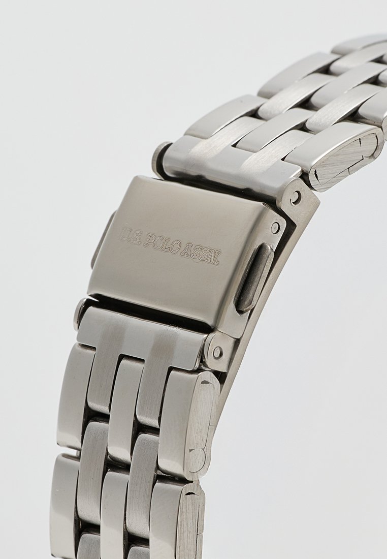 Bracelet de montre en acier inoxydable avec une finition polie, doté d'un fermoir pliant et d'un logo gravé sur le fermoir.