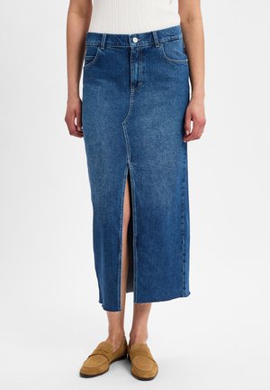 Denim midi skirt with front slit, light blue wash, five-pocket design, high waist, and raw hem finish. Paired with tan loafers.