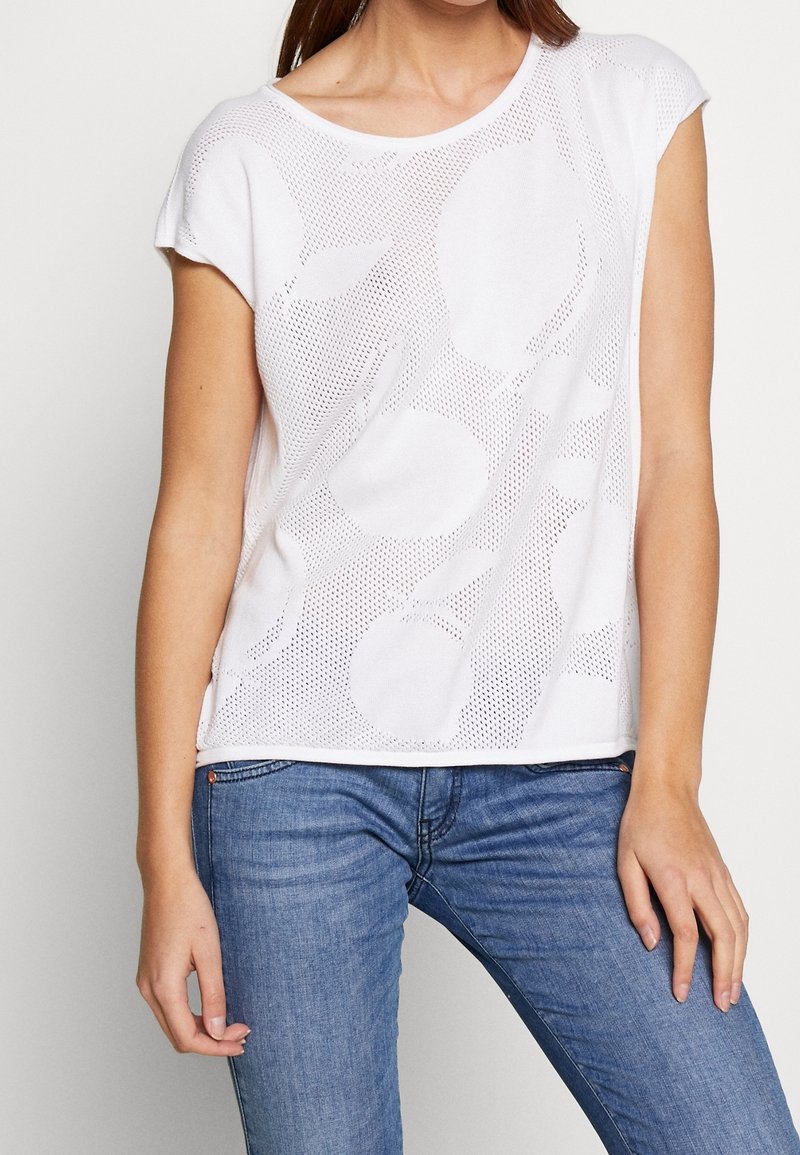 Bílý krátký rukáv top s perforovaným designem a kruhovými vzory. Vyrobeno z lehkého materiálu, má kulatý výstřih a volný střih.