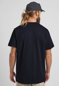 T-shirt in cotone blu navy con maniche corte, vestibilità rilassata, colletto rotondo e design semplice. La vista posteriore non presenta grafiche o dettagli.