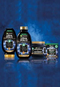 Quattro prodotti Garnier Ultra DOLCE: una bottiglia di shampoo nera, una bottiglia di balsamo nera, una maschera per capelli nera e una scatola di shampoo solido.