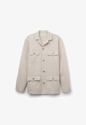 Helle beigefarbene Jacke mit kragen, Knopfverschluss, zwei Brusttaschen und zwei unteren Taschen. Strukturierter Stoff mit einem subtilen Muster.