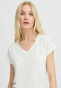 Top a manica corta con scollatura a V di colore avorio, realizzato in tessuto morbido con una superficie liscia. Design semplice, senza fantasie o decorazioni.