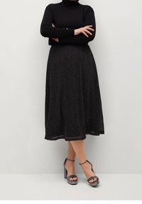 Svart polotröja som matchas med en knälång, glittrig svart kjol. Outfitten har en texturerad tyg och grå högklackade sandaler.