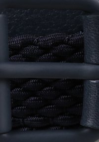 Tessuto intrecciato blu navy fissato da una cornice in plastica scura e opaca. Presenta un accento liscio e strutturato su un lato.