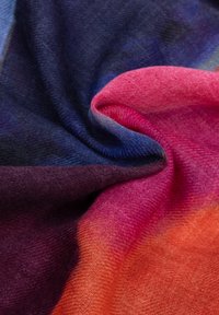 Zachte stof gedraaid, met een verloop van kleuren van donkerblauw en paars naar roze en oranje, waarbij de textuur en weefdetails worden benadrukt.