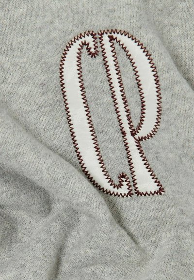 Tessuto a maglia grigio con una superficie testurizzata, caratterizzato da un grande logo ricamato "cp" in bianco, contornato da una cucitura di colore rosso scuro.