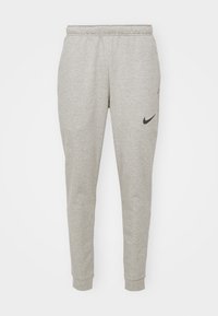 Szare dresy wykonane z miękkiego materiału, z tapered leg design, elastycznym paskiem w talii oraz czarnym logo Nike na lewym udzie.
