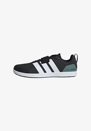 Black athletic shoe with a textured upper, three white stripes, a velcro strap, and a green accent on the heel. Features a rubber sole.