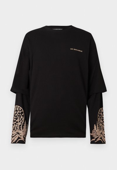 Fekete, hosszú ujjú, réteges póló bézs "LES BENJAMINS" felirattal a mellkason, valamint fa és kunyhó grafikával az alsó ujjrészeken.