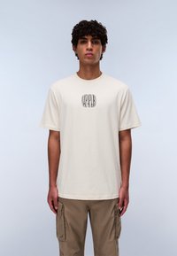 Cream-colored cotton t-shirt with a round neckline, short sleeves, and a central logo design in black. Casual fit with a soft texture.