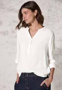 Witte, langarm knoop-shirt met een henleyhalslijn en opgerolde mouwen, gecombineerd met donkerblauwe denim jeans. Zachte stof met een gladde textuur.