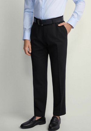 Czarne spodnie garniturowe o dopasowanym kroju, wykonane z gładkiego materiału. Zestawione z jasnoniebieską koszulą z guzikami, czarnym paskiem i butami.