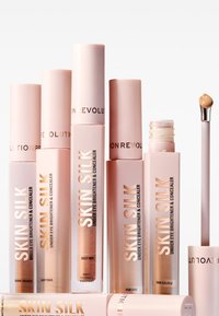 Skin Silk concealers i olika rosa rör. Varje rör har metallisk guldfärgade bokstäver; nyanser inkluderar Deep Red, Fair Cool och Dark Orange.