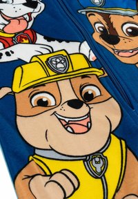 Coperta in pile con personaggi dei cartoni animati su sfondo blu. Il personaggio con il cappello giallo ha un'espressione sorridente e dettagli ben evidenti.