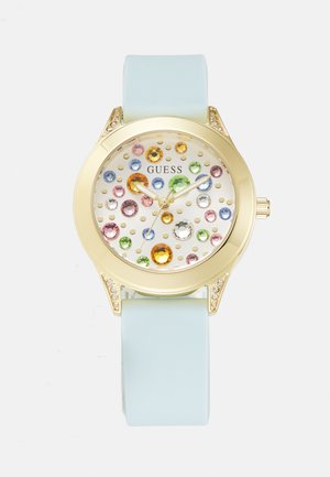Reloj en tono dorado con una esfera blanca que presenta brillantes de colores, manecillas verdes y azules, y una correa de silicona de color azul claro.