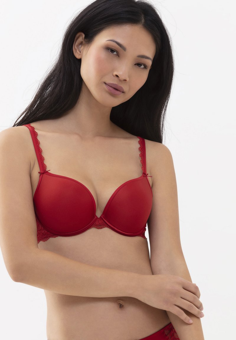 Roter BH mit glatten Körbchen, Spitzenrand an den Kanten und Trägern, gekennzeichnet durch einen tiefen Ausschnitt und dekorative Schleifenakzente.