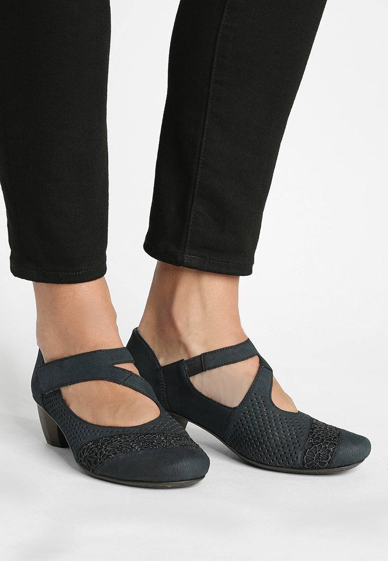 Scarpe blu scuro con un design testurizzato e perforato. Presentano una fascia incrociata e un tacco moderato, realizzate in un materiale morbido.