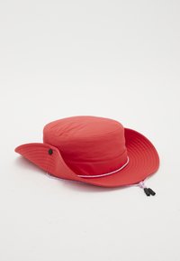 Chapeau seau léger rouge avec un large bord, couronne structurée et cordon de menton ajustable avec des accents violets. Texture douce et lisse.