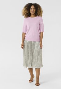 Gaiši rozā īsām piedurknēm blūze ar apaļu kaklu, apvienota ar pleatētu, līdz ceļiem sudraba svārku. Apaviem ir vienkārši siksniņas.